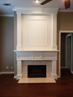 an empty living room with a fireplace and ceiling fan