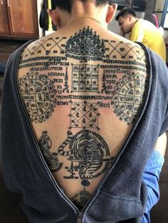 the back of a man's upper body with tattoos on his neck and shoulder