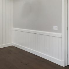 an empty room with white paneling and wood flooring on the walls, along with wooden floors