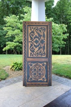 an intricately carved panel on the side of a building with trees in the background