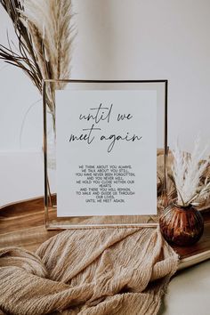 a photo frame sitting on top of a table next to some dried plants and a vase