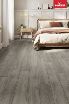 a bedroom scene with focus on the bed and hardwood flooring that looks like wood