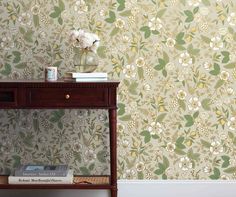 a wooden table with a book on top of it next to a flower wallpaper