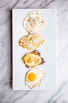 three fried eggs are on a white plate