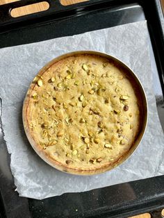 a pizza sitting on top of a pan covered in cheese and pistachios