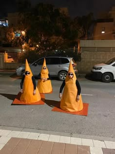 three people dressed in orange cones on the street