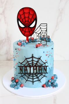 a spiderman birthday cake with blue frosting and sprinkles on it