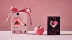 an apple next to a box with a perfume in it and a card that says i love hera