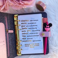 a notebook with some writing on it sitting next to a pink flower and a pen