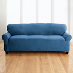 a blue couch sitting on top of a hard wood floor next to a white wall