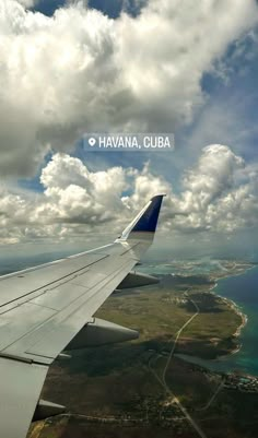 an airplane wing flying over the ocean under a cloudy blue sky with fluffy white clouds