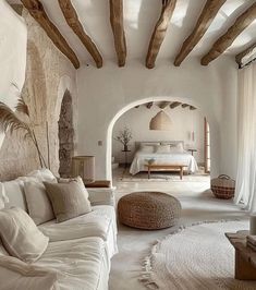 a living room filled with white furniture and lots of natural wood beams on the ceiling