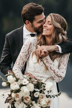 a bride and groom embracing each other in front of water