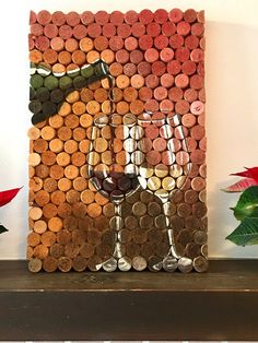 two wine glasses sitting on top of a wooden shelf next to a cork art piece