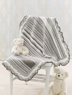 a white teddy bear sitting next to a crocheted blanket on a small chair