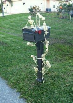 a mailbox with skeleton decorations on it in the grass next to a sidewalk and house