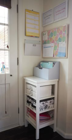 a white desk with drawers and papers on the top shelf in front of a door