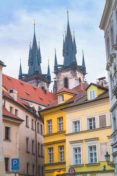 an old city street with tall buildings and spires in the background on a cloudy day