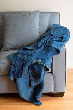 a blue blanket sitting on top of a gray couch