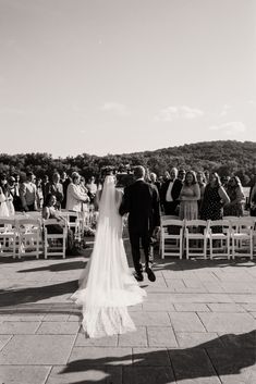 a bride and groom walking down the aisle at their wedding ceremony in black and white