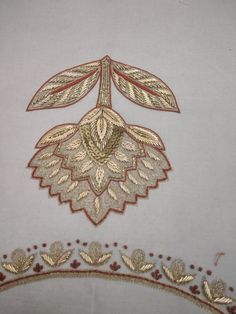 an embroidered design on a white cloth with gold and red trimmings is shown