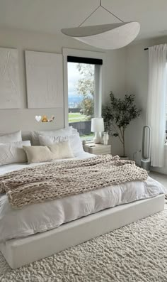 a large white bed sitting in a bedroom next to a window with lots of windows