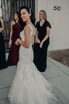 a woman in a wedding dress walking down the street with other women behind her smiling