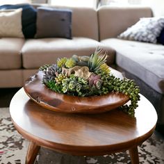 a wooden table topped with succulents on top of a rug next to a couch