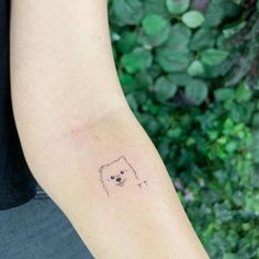 a person with a small tattoo on their arm, holding a dog's head