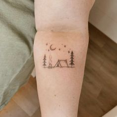 a woman's leg with a small tent and trees tattoo on her left calf