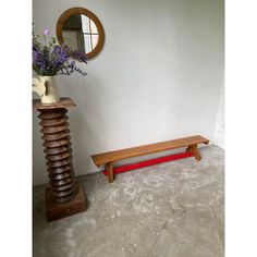 a wooden bench sitting next to a mirror and vase with flowers on top of it