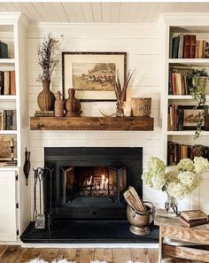 a living room with a fire place and bookshelves on the wall above it