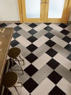 two wine glasses sitting on top of a table in front of an open door and checkered floor