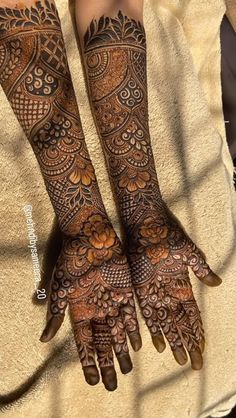 two hands with henna tattoos on them, one is showing the intricate pattern and the other