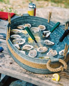 a bucket filled with oysters sitting on top of a wooden table next to other items