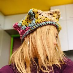 a woman with long blonde hair wearing a crocheted hat