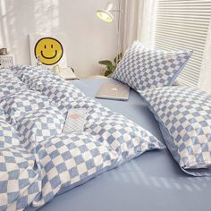 a laptop computer sitting on top of a blue and white checkerboard comforter