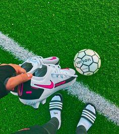 a soccer ball sitting on top of a green field next to two pairs of shoes