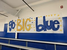 a big blue sign hanging from the side of a wall in a room with metal railings