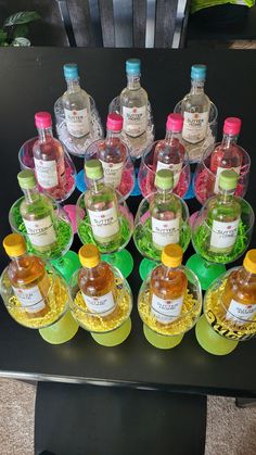 many bottles of alcohol are lined up on a black table with green and yellow circles around them