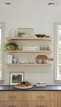 the shelves in this kitchen are filled with plates and bowls, books, and pictures