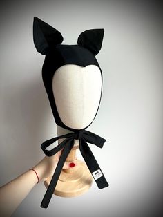 a person holding up a black and white doll with ears on it's head