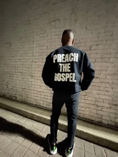 a man standing in front of a brick wall wearing a sweatshirt that says, preacher the gospel