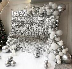 silver and white christmas decorations in front of a wall with a mirror effect behind it