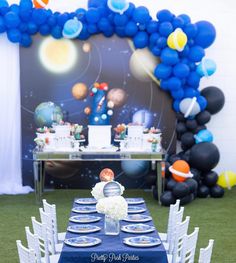 a space themed birthday party with blue and white balloons, silverware, and place settings