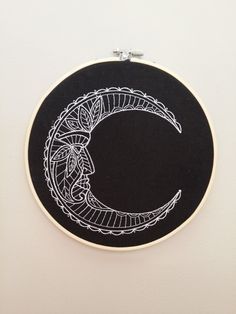 a black and white embroidery on a wall with a circular frame hanging from the wall