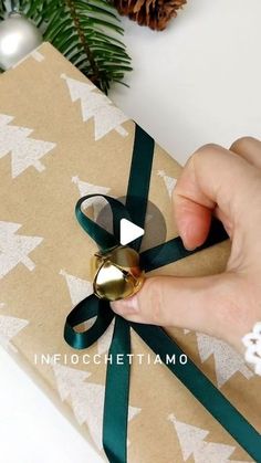 a person opening a gift wrapped in brown paper with a green ribbon and gold bell