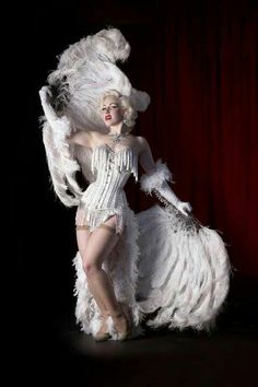 a woman in a white feathered costume posing for the camera with her legs spread out