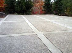 an empty parking lot with trees in the background