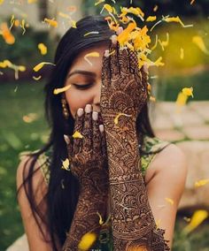 a woman holding her hands up to her face while she is covered in yellow flowers